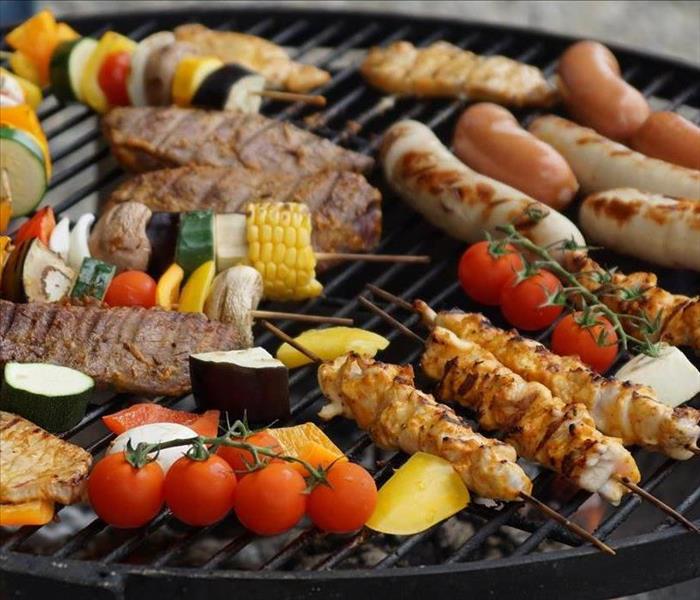 Meat and vegetables on a black round grill. 