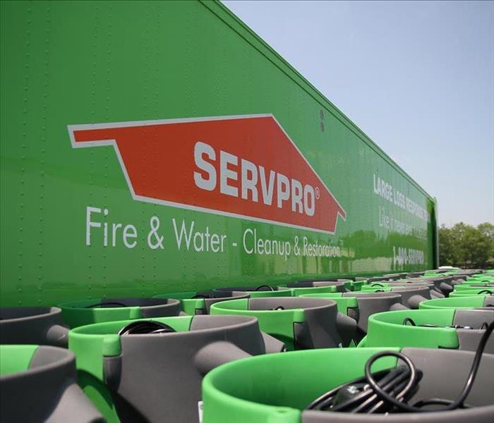 Big green SERVPRO truck with several green air movers in front of the truck.
