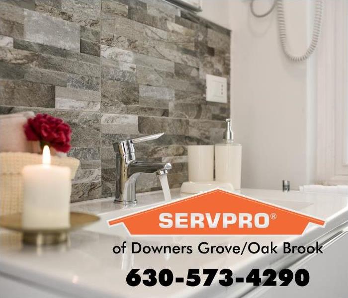 A white bathroom sink with a gray stone backsplash and a white candle.