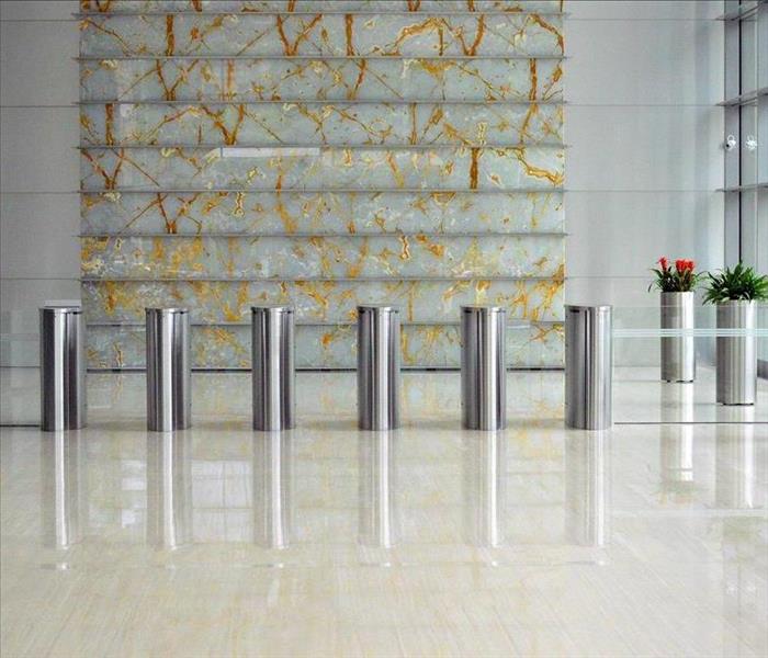 Lobby of an office building with tile floor and silver pillars with flower pots on the side.
